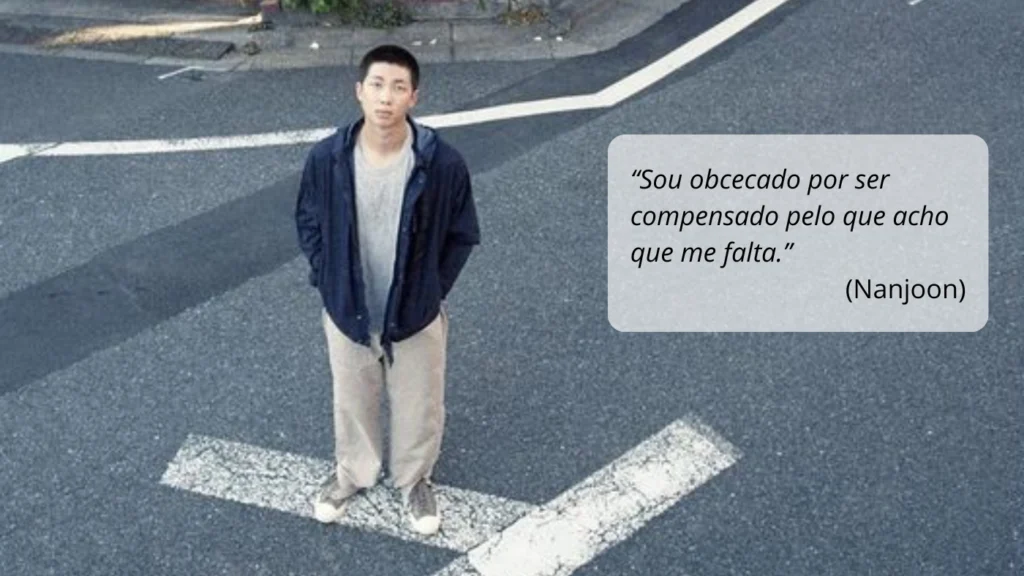 Imagem do documentário *RM: Right People, Wrong Place*, destacando RM em pé no meio de uma rua, com expressão introspectiva, simbolizando sua busca por autenticidade e equilíbrio. Ao lado, a frase "Sou obcecado por ser compensado pelo que acho que me falta" reflete uma de suas reflexões profundas. Publicado por *Bangtan Now*.