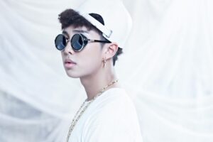 RM no conceito visual do bts o rul82 album, usando óculos estilosos e acessórios dourados que refletem a atitude ousada da era. Descubra mais sobre essa fase marcante no Bangtan Now