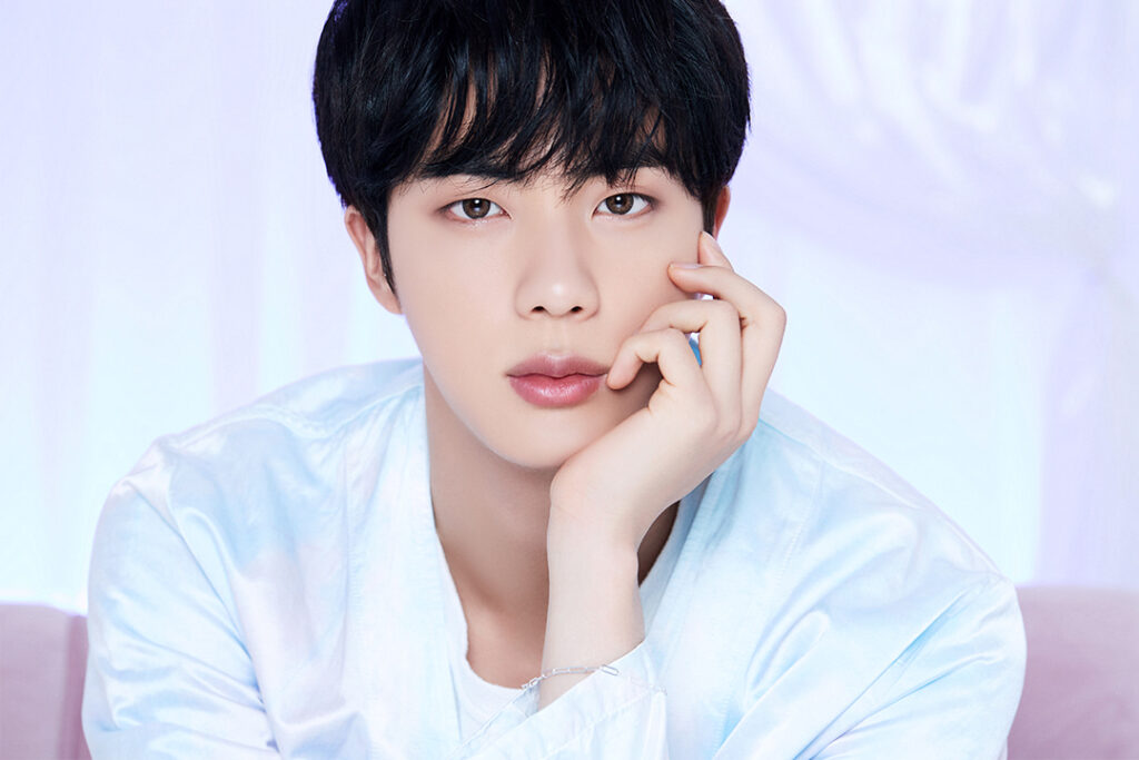 Agradecimentos álbum BE - Bangtan Now (3) Imagem de Jin, integrante do BTS, com uma expressão serena e olhar delicado. Ele veste uma camisa de cetim azul-claro e apoia suavemente o rosto na mão, transmitindo tranquilidade. O fundo branco com iluminação suave realça a atmosfera etérea da foto. Essa imagem faz parte do artigo sobre os agradecimentos de Jin no álbum BE BTS, onde ele expressa gratidão ao ARMY e aos membros do grupo por tornarem possível a criação do álbum. No contexto dos agradecimentos BE BTS, Jin reforça a importância do trabalho em equipe e do apoio mútuo, trazendo sua característica leveza e carinho. Imagem que ilustra o artigo do Bangtan Now.