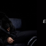 Jin, member of BTS, reclines on a dark leather chair wearing a luxurious black fur coat, against a black background. On the right side, white text reads: "Álbum Echo de Jin – Emotion, flawless vocals, and a gift for the ARMY," under the section header "ALBUMES" and the glowing "Bangtan Now" logo. This promotional image highlights the emotional and artistic depth of the álbum Echo de Jin, featured in a special article by Bangtan Now.