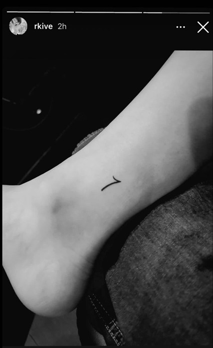 BTS Tatoos - Bangtan Now (5) Black-and-white Instagram Story image shared by BTS member RM (username rkive), showing his minimalist “7” tattoo on the side of his left ankle. This tattoo is part of the shared friendship tattoos among all BTS members. The image is featured in a Bangtan Now article exploring BTS Tattoos and the meanings behind them.