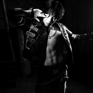 Black-and-white concept photo of j-hope for Killin it Girl music, showing him with an open leather racing jacket and bare torso, striking a confident pose with one arm raised over his face. This bold visual, featured in the Bangtan Now article, highlights the edgy and empowered aesthetic of the new era.