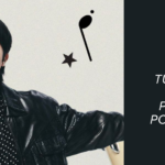 Imagem promocional de Jin usada como capa do artigo no blog Bangtan Now, sobre a Tour Jin. Jin aparece de braços abertos, vestindo jaqueta de couro preta, camisa listrada e fone de ouvido, com elementos gráficos musicais ao fundo. À direita, o texto destaca: "Tudo sobre a primeira turnê solo do Jin – e porque só ele mesmo pode criar algo assim!".
