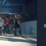 Imagen de portada del artículo del blog Bangtan Now sobre la canción BTS Fire. La imagen es una captura de escena del videoclip oficial, que muestra a los siete integrantes de BTS bailando dentro de una piscina vacía, con azulejos de color azul claro en las paredes. Están en formación coreográfica, con expresiones intensas y los cuerpos en movimiento sincronizado. La iluminación proviene de una abertura en el techo, creando un haz de luz que entra por la izquierda de la imagen. Todos llevan ropa de estilo streetwear, con chaquetas estampadas y pantalones negros rasgados. En el lado derecho de la imagen, sobre un fondo azul oscuro, aparece el logotipo de Bangtan Now en la parte superior, la palabra “ÁLBUMES” en letras blancas y el título del artículo en destaque: “BTS Fire – Traducción, significado y todo sobre la canción que incendió al ARMY”.