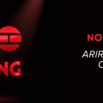 Imagem gerada por IA mostrando o logo do álbum ARIRANG do grupo BTS. O logo possui três círculos vermelhos brilhantes com detalhes em branco. Abaixo, está escrito "ARIRANG" em letras vermelhas grandes. No lado direito da imagem, há o título "NOVO ÁLBUM DO BTS" em vermelho maiúsculo, seguido do subtítulo em branco itálico: "Arirang - tudo sobre o lançamento de março de 2026". No canto superior direito aparecem os logos "ARTIGOS" e "Bangtan Now".