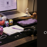 ARMY BOMB iluminada em roxo no centro de um setup de ARMY: photocards, álbum Map of the Soul, miniaturas BT21 e acessórios K-pop sobre mesa escura.