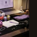 ARMY BOMB, BTS official lightstick, on a desk with BT21 plushies and photocards