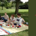 Os sete integrantes do BTS sentados lado a lado em toalhas de piquenique coloridas, sobre a grama de um parque arborizado com um lago ao fundo. Eles riem e conversam entre cestas de vime, pratos de comida e copos vermelhos. Ao lado, sobre fundo verde-oliva, o título do artigo do Bangtan Now: Cancelamento no BTS: quem salva o salvador?